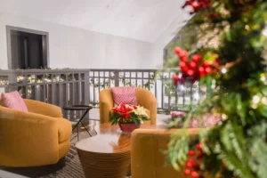 Yellow chairs arranged around a Christmas tree decorated with lights and ornaments in a cozy room.