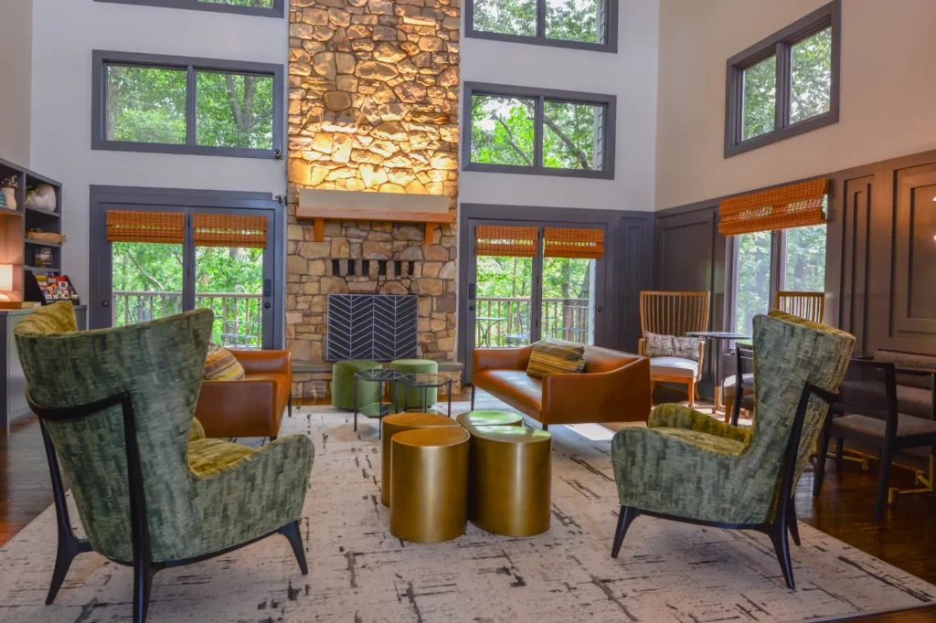 A lobby with a stone fireplace and green chairs.